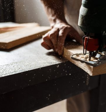Close up photo of cutting wood with fretsaw over dark background. Copy space.